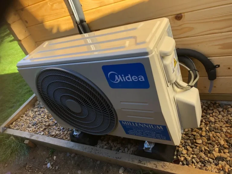 Midea outdoor unit with a Millennium service label beside a timber garden room